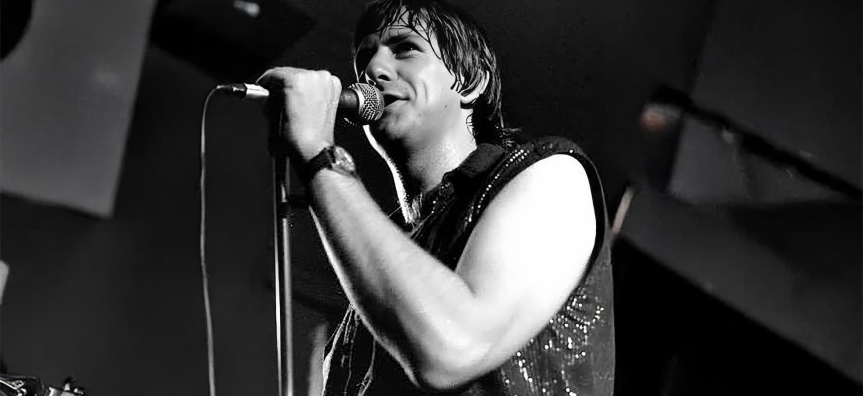 Performer singing into a microphone on stage.